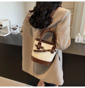 Détail d'un sac seau rétro avec patchwork crème et marron et une boucle mors dorée