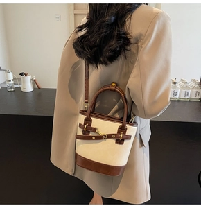 Détail du mini sac seau en toile porté en bandoulière par un mannequin en costume beige