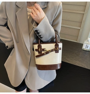 Détail du sac seau contrasté avec lanières en cuir marron et boucle métallique chic