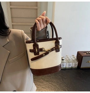 Détail d'un sac seau rétro bicolore crème et marron avec des finitions en métal