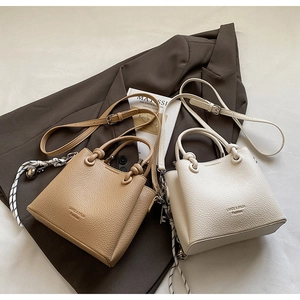 Detail of lychee pattern leather mini bucket bags in brown and beige with knotted handles
