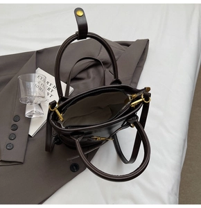 Détail d'un sac seau en cuir marron foncé avec fermeture éclair et pièces métalliques
