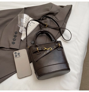 Vue détaillée du sac seau en cuir mat marron foncé avec boucle dorée et bandoulière