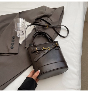Détails du sac seau en cuir marron foncé avec ferrures en bronze rétro et texture riche