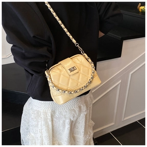 Détail d'un sac matelassé beige avec chaîne argentée porté sur une tenue élégante
