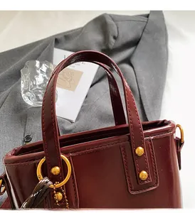 Detailed macro view of deep wine red tote bag with reinforced handles and gold hardware