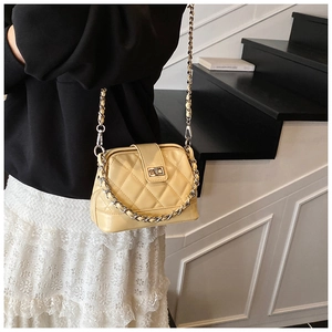 Détail du sac matelassé crème avec bandoulière bicolore porté par un mannequin