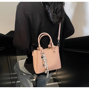 Sac seau rose à grain de litchi avec poignée nouée et foulard porté par le modèle