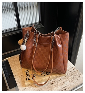 Detailed macro view of the brown checkered tote bag with silver chain and baseball charm