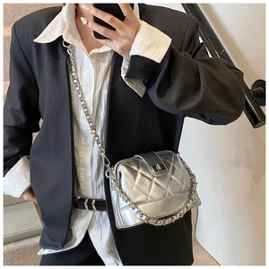 Sac bandoulière argenté à motif matelassé porté à l'épaule dans un cadre d'intérieur chic