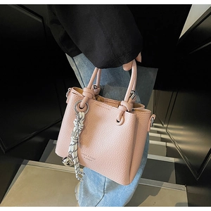 Sac seau en cuir grainé rose avec poignée nouée et breloque cloche argentée élégante