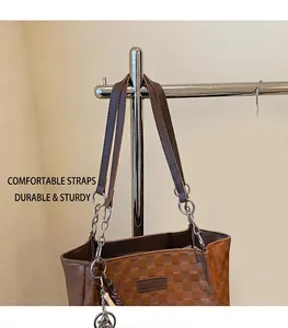 Detail of checkered tote bag with brown leather and silver chain strap for shoulder wear