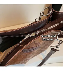 Detail of silver metal zipper and brand leather tag on the checkered brown tote bag