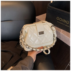 Détail d'un sac bandoulière matelassé crème avec chaîne argentée et fermoir en métal