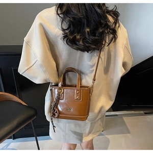 Detail of a dark brown mini leather bucket bag with metallic studs and logo branding