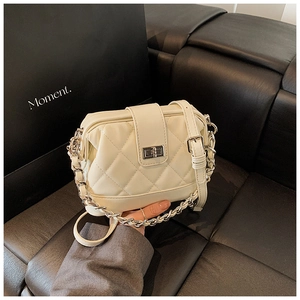 Détails de la texture en cuir matelassé et fermoir rotatif argenté du sac à bandoulière