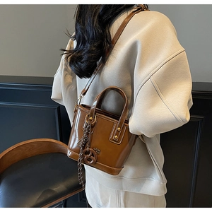 Close-up of brown bucket bag with gold ring hardware and logo detail on leather