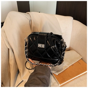 Détail d'un sac bandoulière matelassé noir avec fermoir argenté et bandoulière chaîne