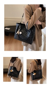 Detail of black checkered tote bag featuring a spherical charm and dual shoulder straps
