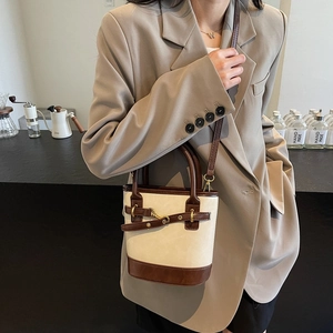 Sac seau chic beige et marron avec boucle mors dorée porté par un mannequin