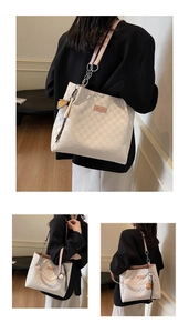 Detail of white checkered tote bag featuring pink leather straps and hanging ornaments