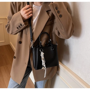 Detail of black lychee grain bucket bag with a striped silk scarf handle accent