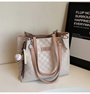 Detail of beige plaid tote bag with pink handles and baseball charm accessory