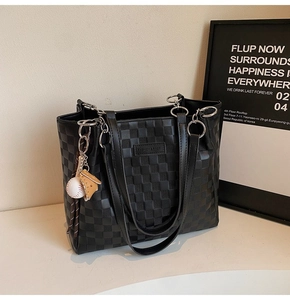 Detail of black tote bag with embossed plaid texture and baseball themed charms