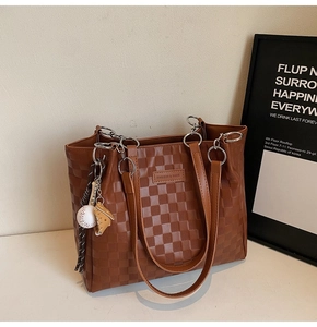 Close-up of brown checkered tote bag with fashion tag and sports theme charm detail