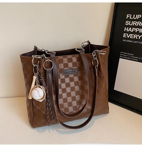 Detail of checkered tote bag with leather logo patch and baseball charm accessory