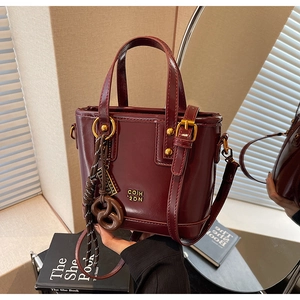 Detailed close-up of wine red polished leather mini tote bag with cute pretzel charm