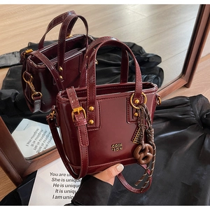 Detailed macro view of glossy burgundy leather bucket bag with a pretzel charm