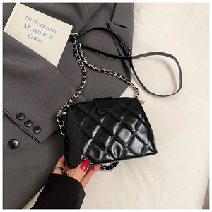 Détails de la texture matelassée noire et de la chaîne argentée du sac à bandoulière