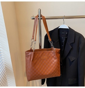 Detailed view of brown woven texture on a tote bag with metallic chain accents