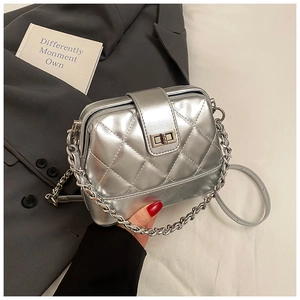 Détail du sac bandoulière argenté matelassé avec fermoir rotatif et bandoulière chaîne