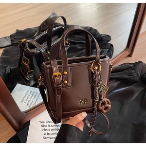 Detailed macro of dark brown PU leather bucket bag with gold hardware and woven rope detail
