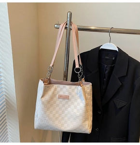 Detail of checkered tote bag featuring pink leather straps and silver chain link accents