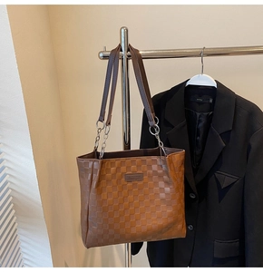 Close-up of brown checkered tote bag with leather straps and metal chain detail
