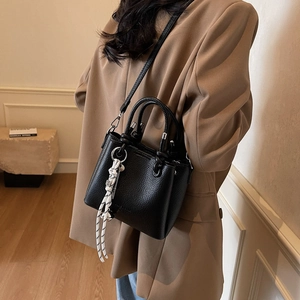 Chic black bucket bag in pebble leather with striped scarf accessory and top handle
