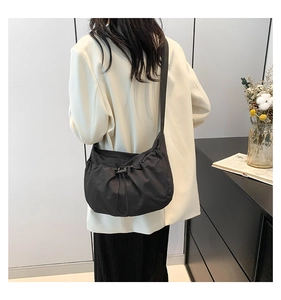 Detail of black drawstring pleated crossbody bag made of lightweight nylon fabric