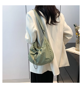 Detail of light green drawstring crossbody bag showing light fabric and adjustable strap
