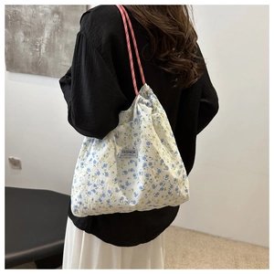 Detail of floral drawstring tote bag featuring seersucker texture and braided shoulder straps