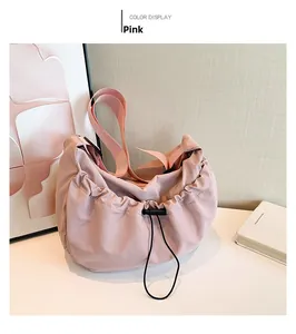 Pink drawstring nylon crossbody bag with wide shoulder strap in a stylish minimalist setting
