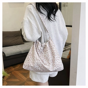 Detail view of floral canvas shoulder bag with drawstring closure and wide strap design