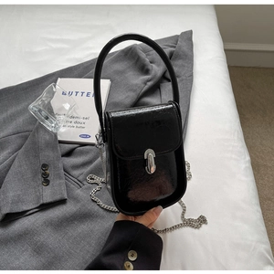 Close-up of a mini black glossy chain bag with silver capsule clasp and metal handle