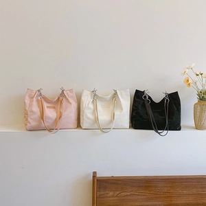 Trois sacs cabas minimalistes texturés en rose, blanc et noir avec anneaux argentés
