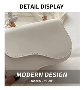 Close-up of white leather saddle bag showing woven handle and golden metal hardware detail
