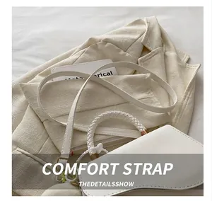 Close-up of white leather crossbody bag featuring a woven handle and floral charm