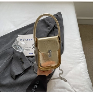 Close-up of golden metallic textured mini bag with silver chain and twist lock detail