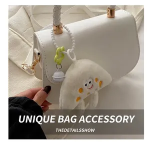 Detail of plush cream charm with yellow polka dots and star hook on white woven bag